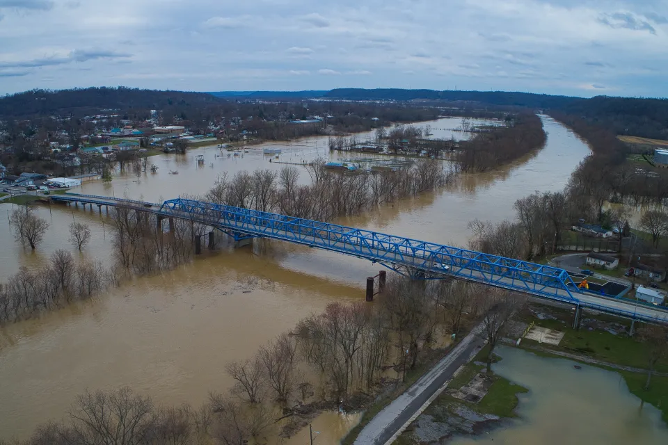 Aerial view of a blue bridge over a wide, flooded river in Kentucky.